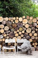 Garden chairs by wall of logs