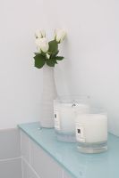 Candles and flowers on bathroom shelf 