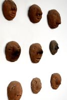 Collection of clay heads on wall, detail