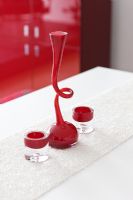 Detail of red curvy candle stick and tea light holders on white table