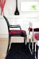 Black glossy dining chair with red patterned cushion on rug