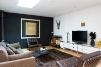 Contemporary living room with leather armchairs and black feature wall