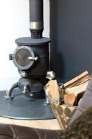 Small round wood burning stove by black wall