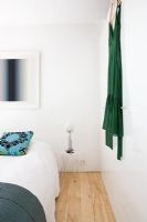 Bedroom with turquoise patterned cushion and green dress hanging on the wall