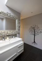 Sink unit, ornate mirror and tree wall mural in bathroom