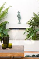 Water feature in urban garden with statue on built in shelf above