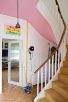Hallway with pink walls and curved staircase