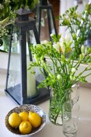 Lemons in bowl next to vase of flowers
