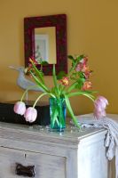 Vase of Tulips on wooden painted chest of drawers
