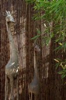 Wooden giraffe sculptures by bamboo fence