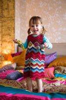 Little girl bouncing on colourful bed