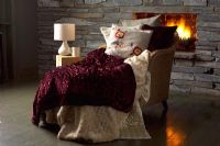 Textured throws on chair by fire