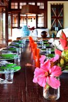 Tropical flowers on long wooden dining table set for meal

