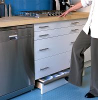 Woman using low level storage in contemporary kitchen