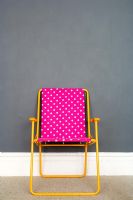 Colourful folding chair against grey wall