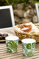 Garden table with patterned cups and pastries in basket