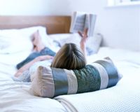 Woman lying on bed reading book 