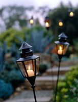 Lanterns with burning candles in garden 