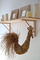 Detail of straw cockerel hanging from shelf 