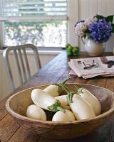 White aubergines in wooden bowl on dining table