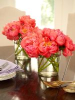 Glasses of flowers on dining table 