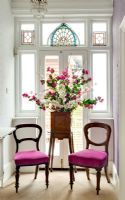 Flower stand and chairs by stained glass window