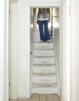 Person walking down distressed white staircase 