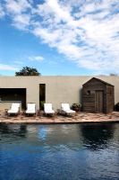 Sun loungers around modern swimming pool 