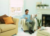 Man sitting reading newspaper in living room 