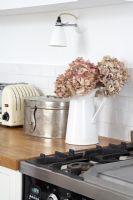 Jug of dried flowers on kitchen worktop 