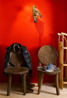 Two rustic wooden chairs by red wall 