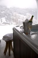 Ice bucket with champagne on edge of hot tub 