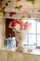Stone vase of flowers on bathroom windowsill