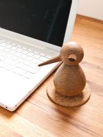 Wooden bird next to laptop computer 