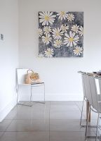 White chair and floral painting in corner of dining room