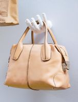 Tod handbag displayed on wall mounted sculpted hand