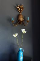 Vase of flowers under pineapple wall sconce