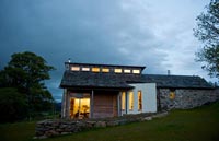 Farmhouse with modern extension lit up at night