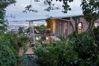 Contemporary house and tropical garden lit up at dusk