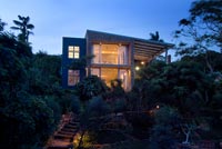 Contemporary house and tropical garden lit up at night