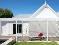 White house with lounger under pergola