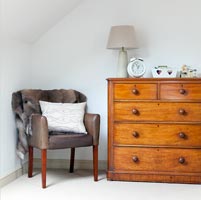 Modern armchair next to chest of drawers
