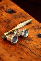 Antique opera glasses on wooden surface