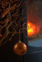 Christmas arrangement of berries, twigs and baubles by fire
