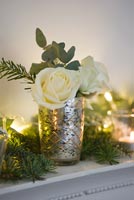 Roses and seasonal foliage in silver glass