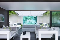 Contemporary lounge area under weather proof canopy with video screen projected on wall - RHS Chelsea Flower Show 2012 