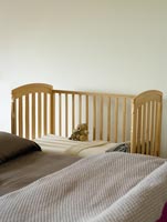Wooden cot by bed