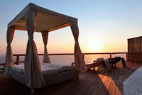 Four poster bed on terrace overlooking sea