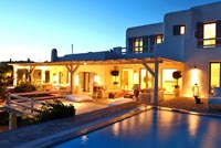 Greek villa and pool lit up at night
