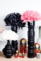 Paper flowers arranged in tall black vases